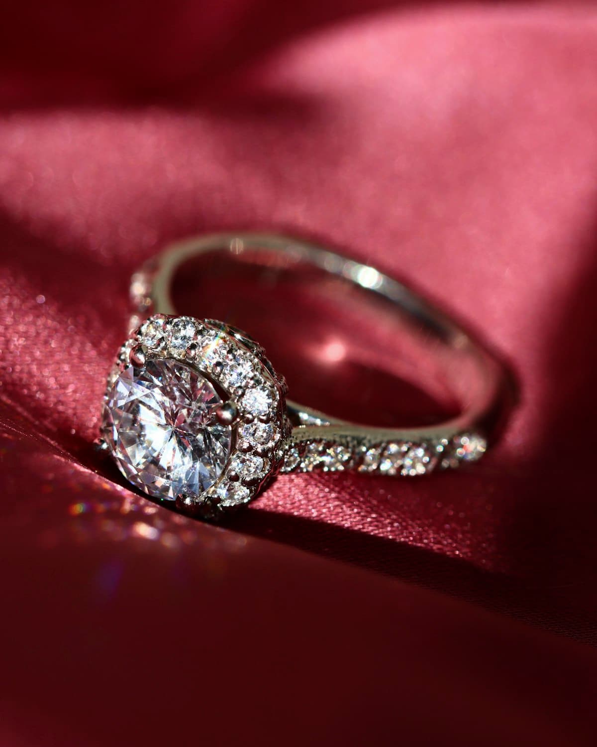A fine diamond ring resting on deep red velvet in a softly lit display case